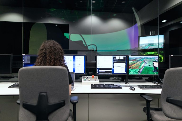 The Role of Automated Regression Testing in Software Development 1 A person monitoring multiple screens filled with graphs and interfaces in a dark control room, symbolizing the complexity of software development and testing. #Regression Testing