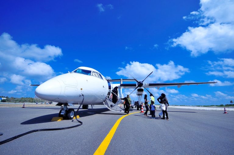 Passengers boarding a twin-propeller private jet on a sunny tarmac