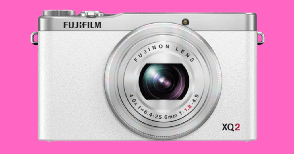 Fujifilm XQ2 Review: Compact and Powerful 2 A sleek black Fujifilm XQ2 camera against a white background, showcasing its compact and powerful design. Text reads: "Fujifilm XQ2 Review: Compact and Powerful.
